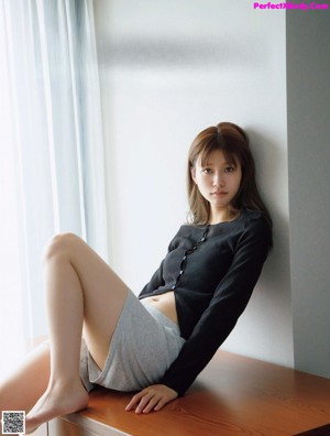 A woman in a brown sweater is posing for a magazine.