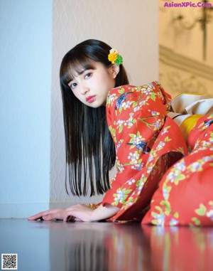 A woman in a red kimono sitting on a gold chair.