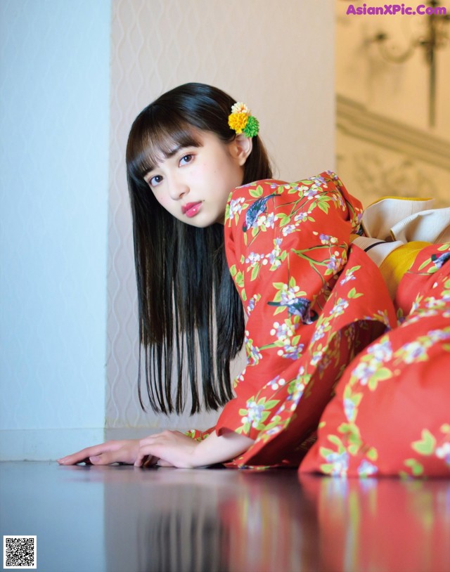 A woman in a red kimono laying on the floor.