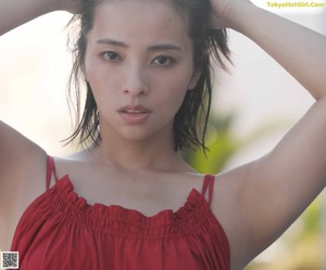 A woman in a maroon swimsuit standing on the beach.