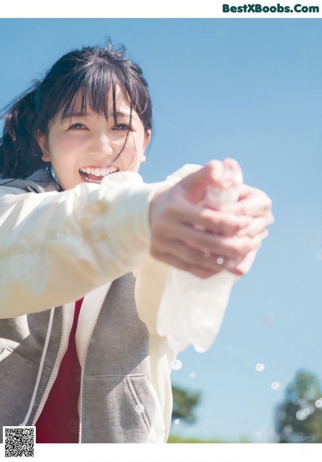 A woman in a white jacket is holding a soap bubble.