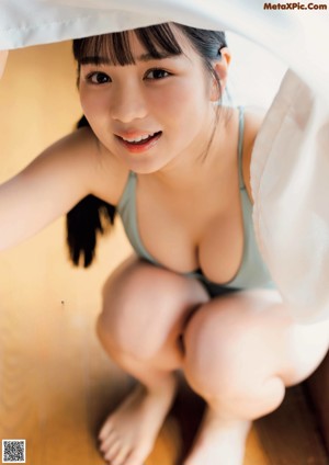 A naked woman sitting on the floor holding a glass of water.