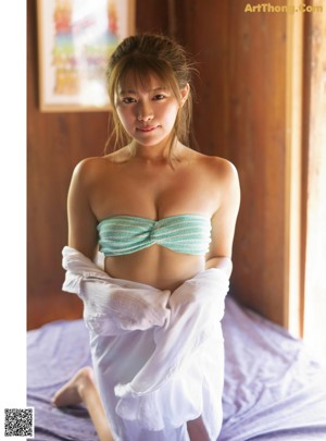 A woman in a blue bikini sitting on the beach.