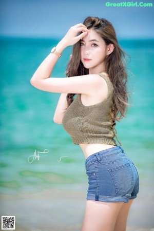 A woman sitting on top of a rock next to the ocean.