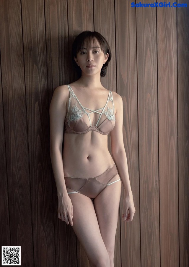 A woman standing in front of a wooden wall.
