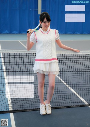 A woman in a white sweater is posing for a picture.