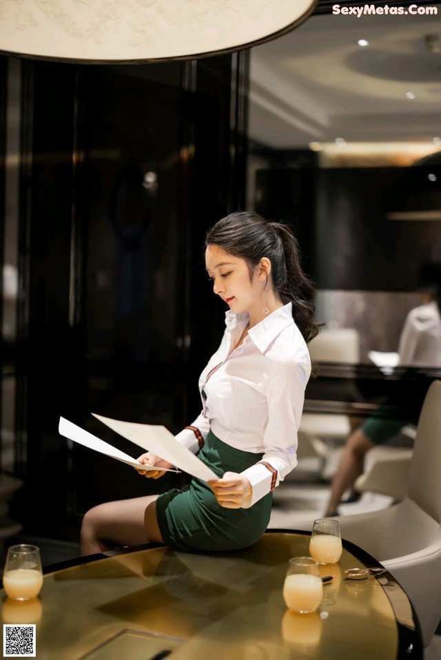 A woman sitting at a table reading a book.