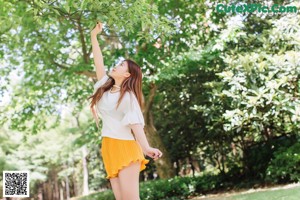 A young woman leaning against a tree in a park.