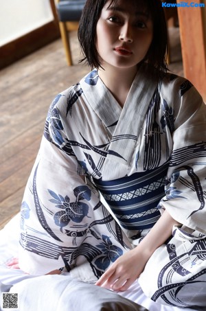 A naked woman laying on a tatami mat in front of a window.