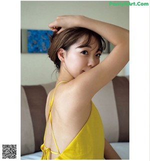 A woman in a yellow dress sitting on a bed.