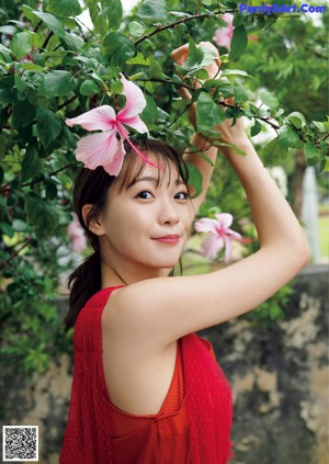 A woman in a red dress standing in front of a tree.