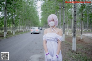 A woman in a white dress standing on the side of a road.