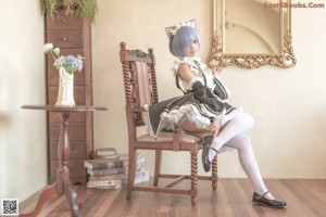 A woman in a maid outfit sitting on a bed.