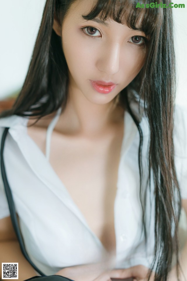 A woman with long black hair wearing a white shirt.