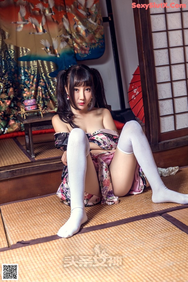 A woman in a kimono sitting on a tatami mat.