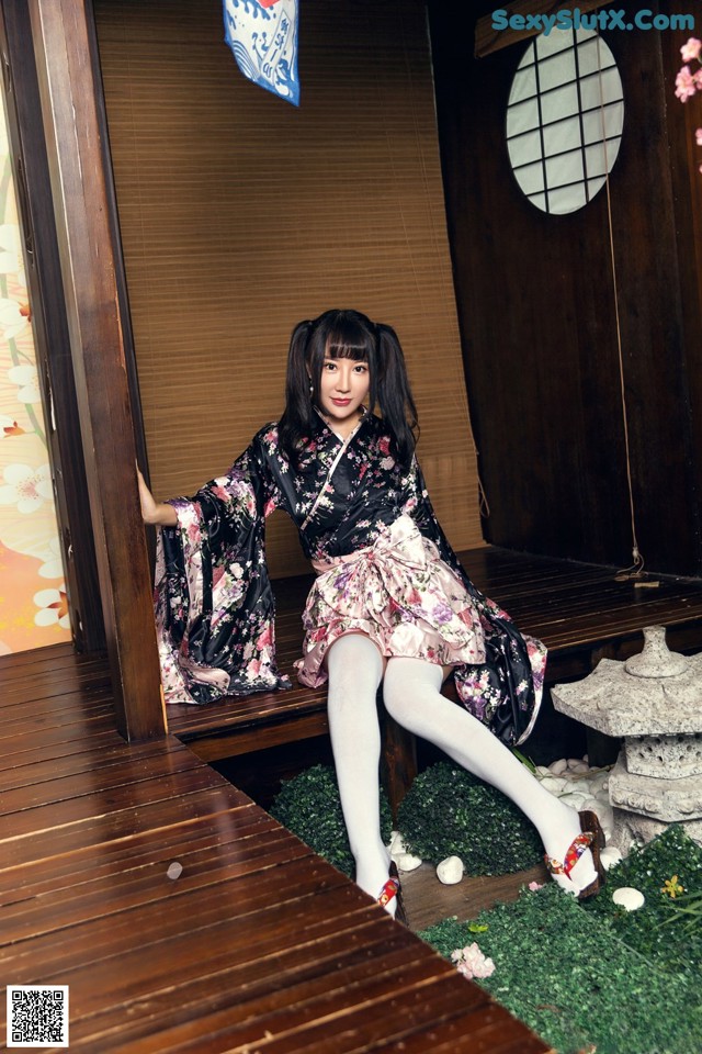 A woman in a kimono sitting on a wooden bench.