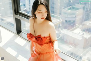A naked woman sitting in a bathtub next to a window.