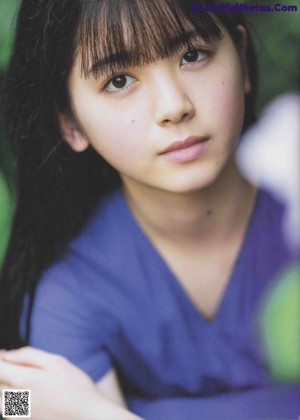 A young woman in a blue dress sitting on the ground.