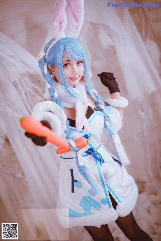 A woman dressed in a bunny costume holding a carrot.