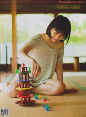 A woman in a white shirt and black skirt sitting on a tatami mat.