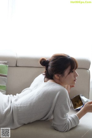 A woman sitting on a couch eating a piece of food.