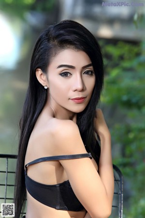 A naked asian woman leaning on a fence.