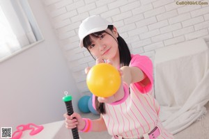 A woman in a pink and white striped outfit holding a baseball bat.