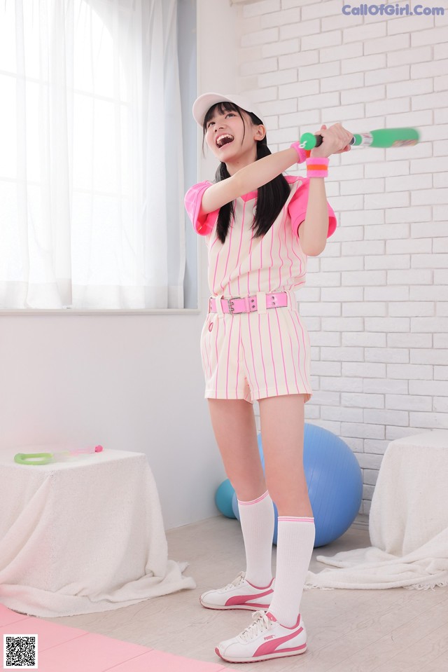 A woman in a pink and white striped outfit holding a baseball bat.
