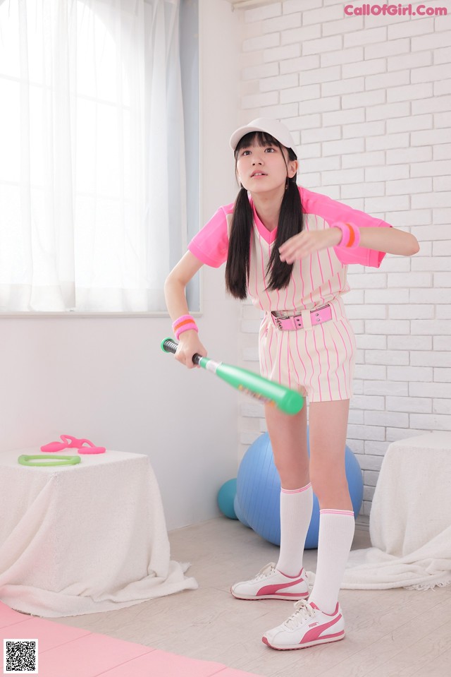 A woman in a pink and white striped outfit holding a baseball bat.