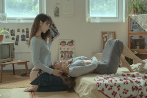 A couple of women sitting on top of a bed.