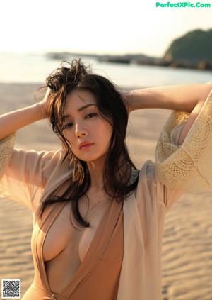 A woman in a brown bathing suit standing on a beach.