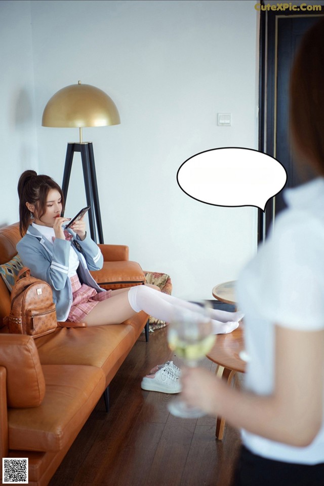 A woman sitting on a couch looking at her cell phone.