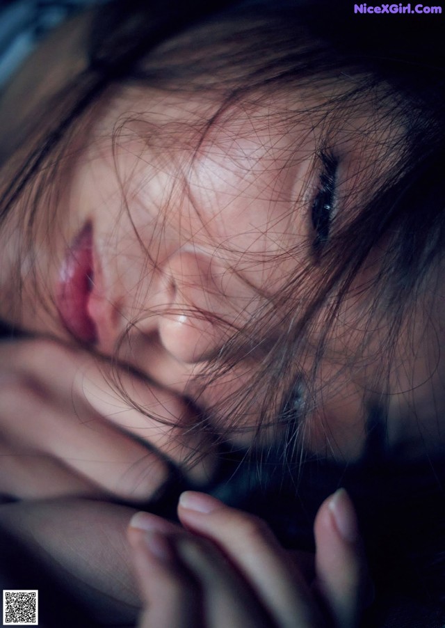 A close up of a woman's face with her hands on her face.