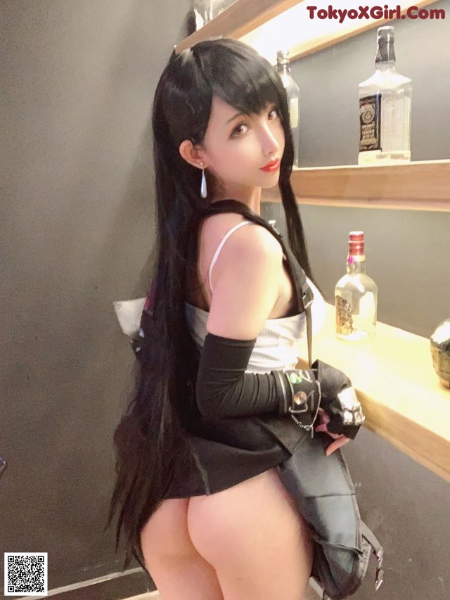 A woman with long black hair standing in front of a bar.