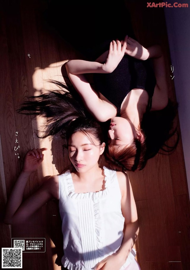 A couple of women laying on top of a wooden floor.