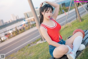 A woman in a red tank top and denim shorts holding a basketball.