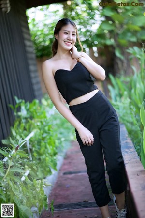 A woman in a black dress standing on the edge of a swimming pool.