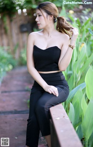 A woman in a black dress standing on the edge of a swimming pool.
