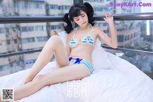 A woman in a blue and white bikini laying on a bed.