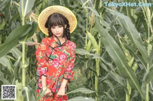 A woman in a red dress and a straw hat posing for a picture.