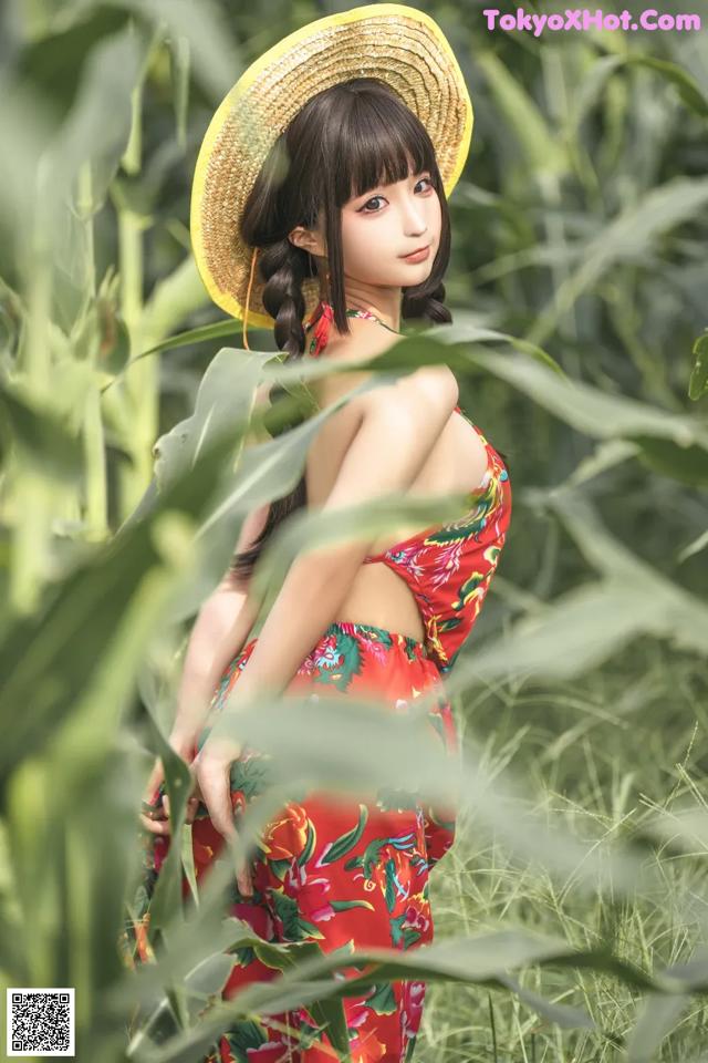 A woman in a straw hat standing in a field of tall grass.