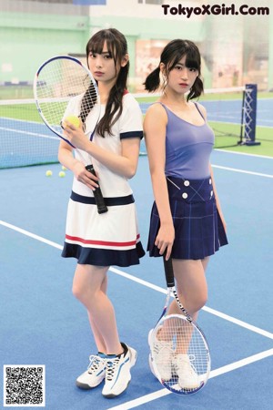 Two young women posing for a picture on a tennis court.