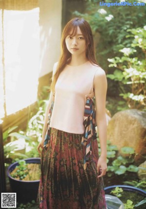 A woman with long brown hair sitting on a wooden bench.