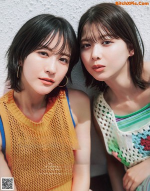 A couple of women laying on top of a bed next to each other.