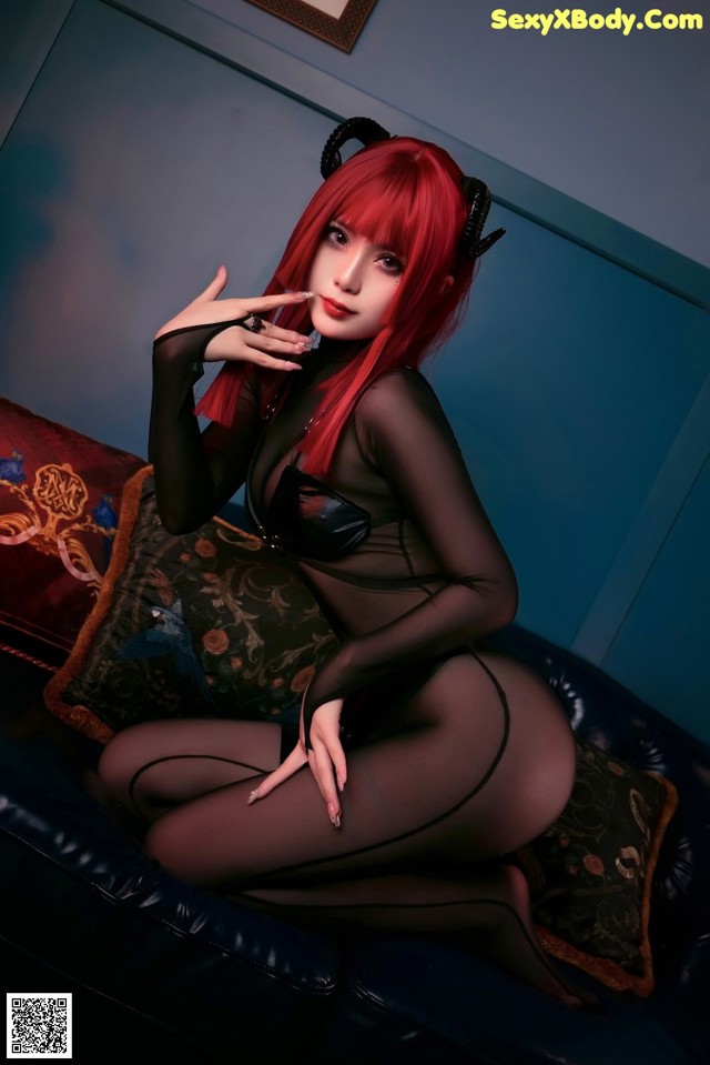 A woman with red hair sitting on a black couch.