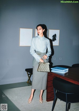 A woman in a black coat and pink shoes sitting on a chair.