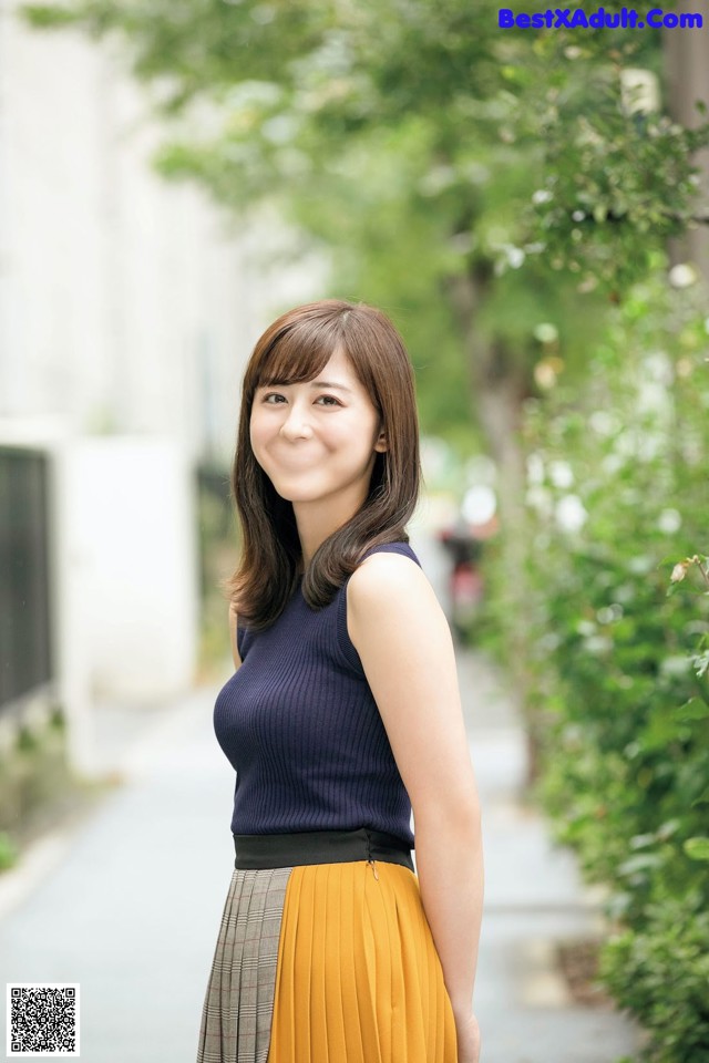 A woman in a blue top and yellow skirt posing for a picture.