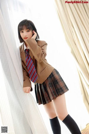 A woman in a white shirt and stockings leaning against a wooden cabinet.