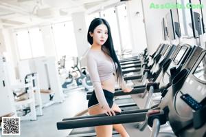 A woman sitting on a stationary bike in a gym.