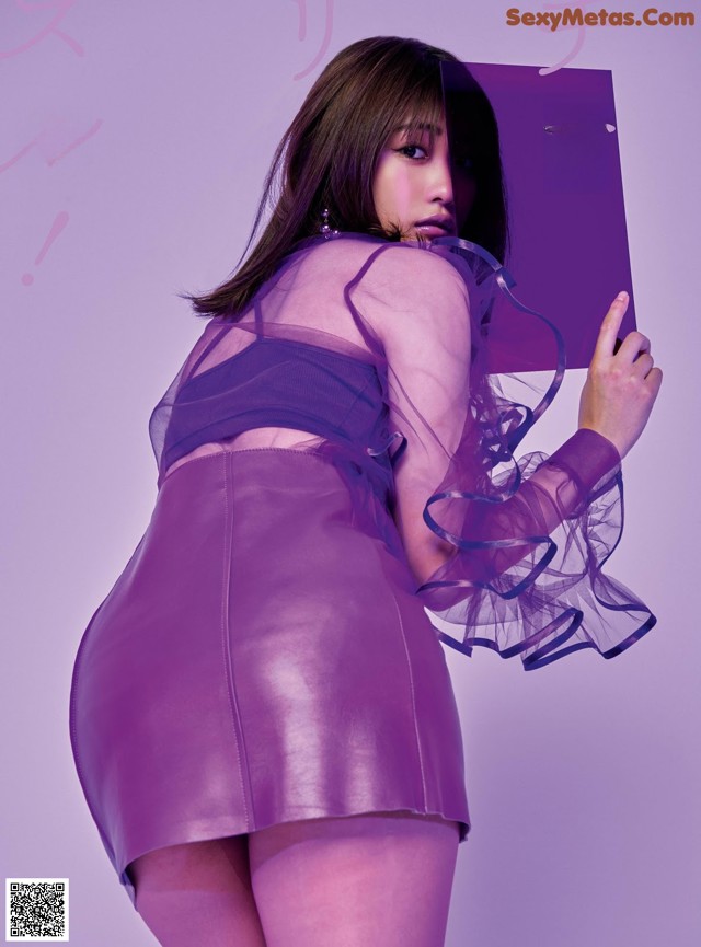 A woman in a purple dress holding a purple book.